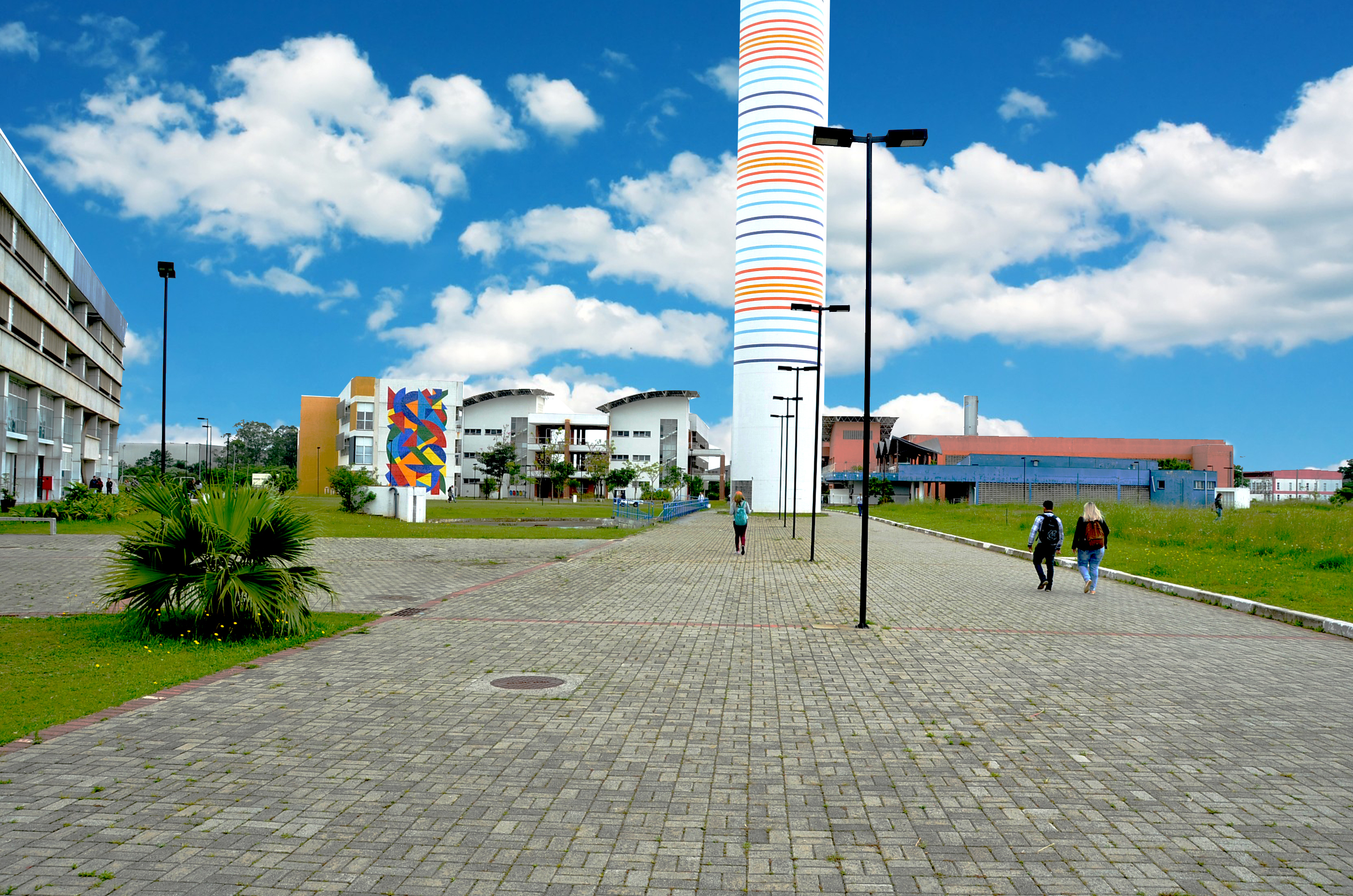 campus universitário com céu azul e trêz prédios brancos